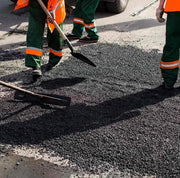 Operarios extendiendo y compactando asfalto en frío Vetonek en la reparación de un bache