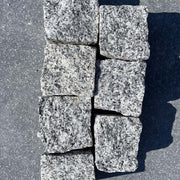 Adoquines de granito gris rústico ideales para jardines y caminos decorativos.