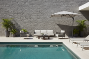 Muro exterior revestido con Aplacado Dordogne en un patio de lujo con piscina y muebles de exterior