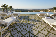 Terraza de piscina con Adoquín Chinchón Triangular de hormigón en gris natural y césped entre las piezas - Vetonek